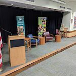 Thumbnail: Side angle looking at the platform stage with the US flag, podium, chairs, and marketing banners up on the stage.