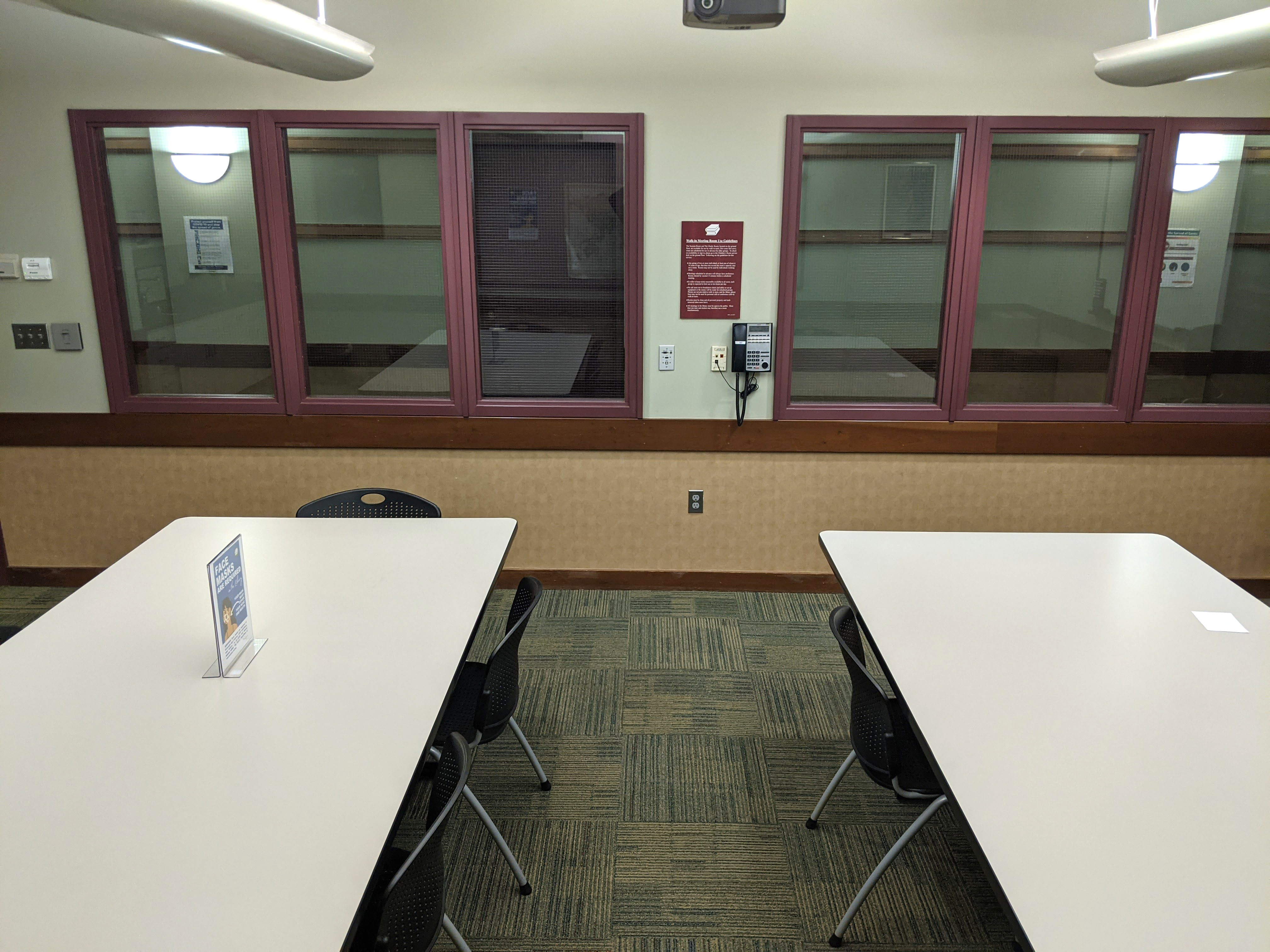 Tables and chairs looking towards the rear of the room, from the projector screen side of the room.