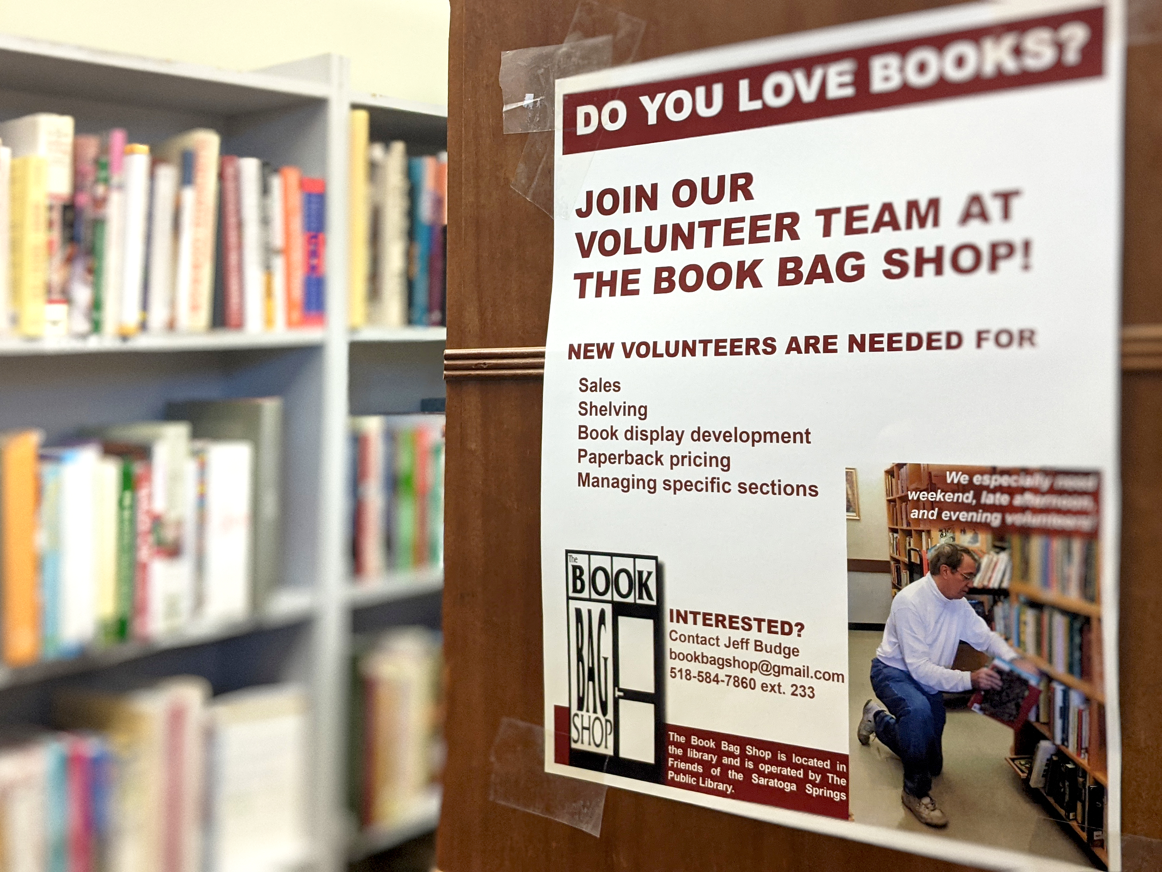 A paper sign taped to a shelf looking for volunteers to help work at the book shop.