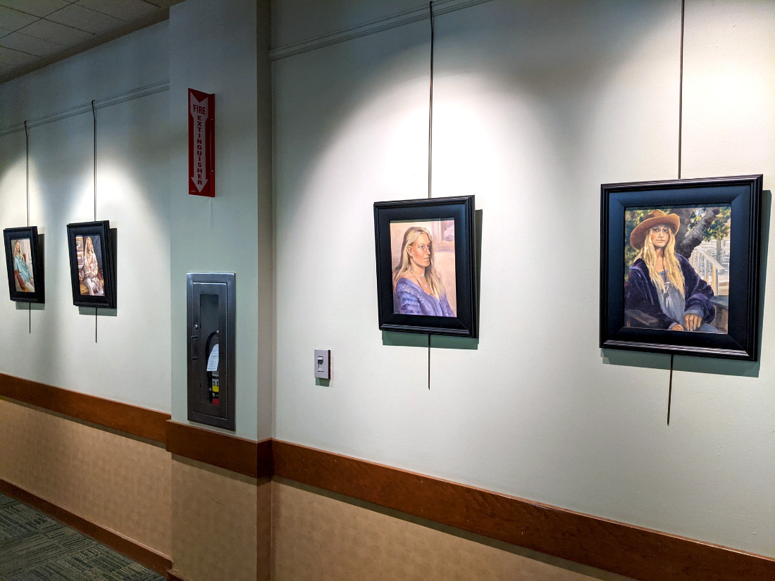 Artwork hanging on the wall is individually lit by an overhead spotlight.