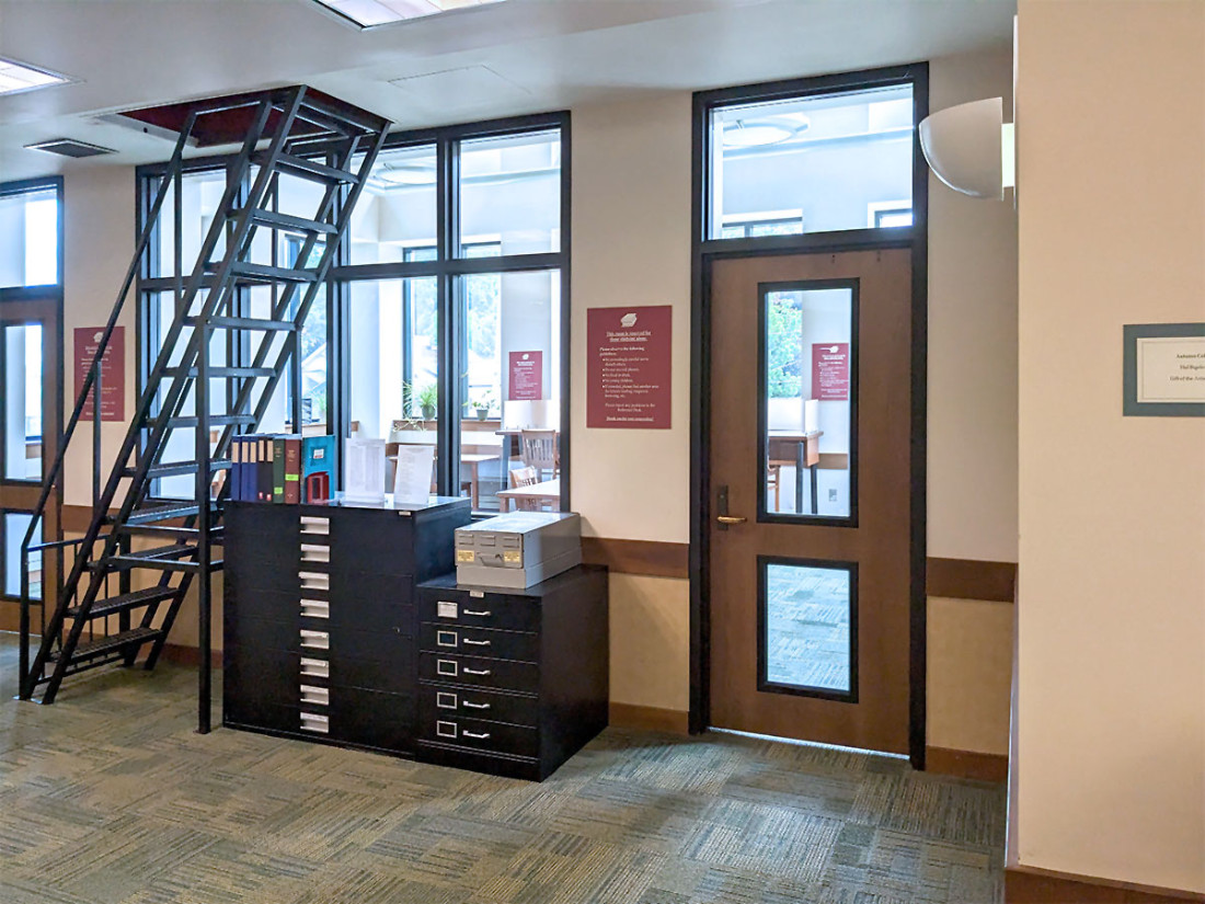 Metal storage drawers with labels, a metal staircase ladder, and a wooden door with windows used as an entryway.