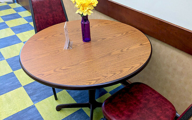 Two red, leather-cushioned seats surround a small circular table with a floral centerpiece.