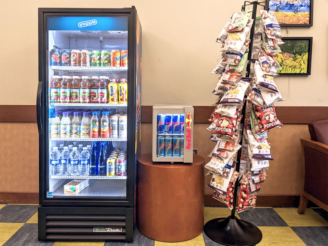 Fully stocked refrigerated drink storage, and chip bag stand.