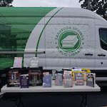 Thumbnail: A panel van, decorated with the library’s colors of green and white showcasing a two-tone photo depicting the library all in green on the back half and the library logo in green on white on the front.